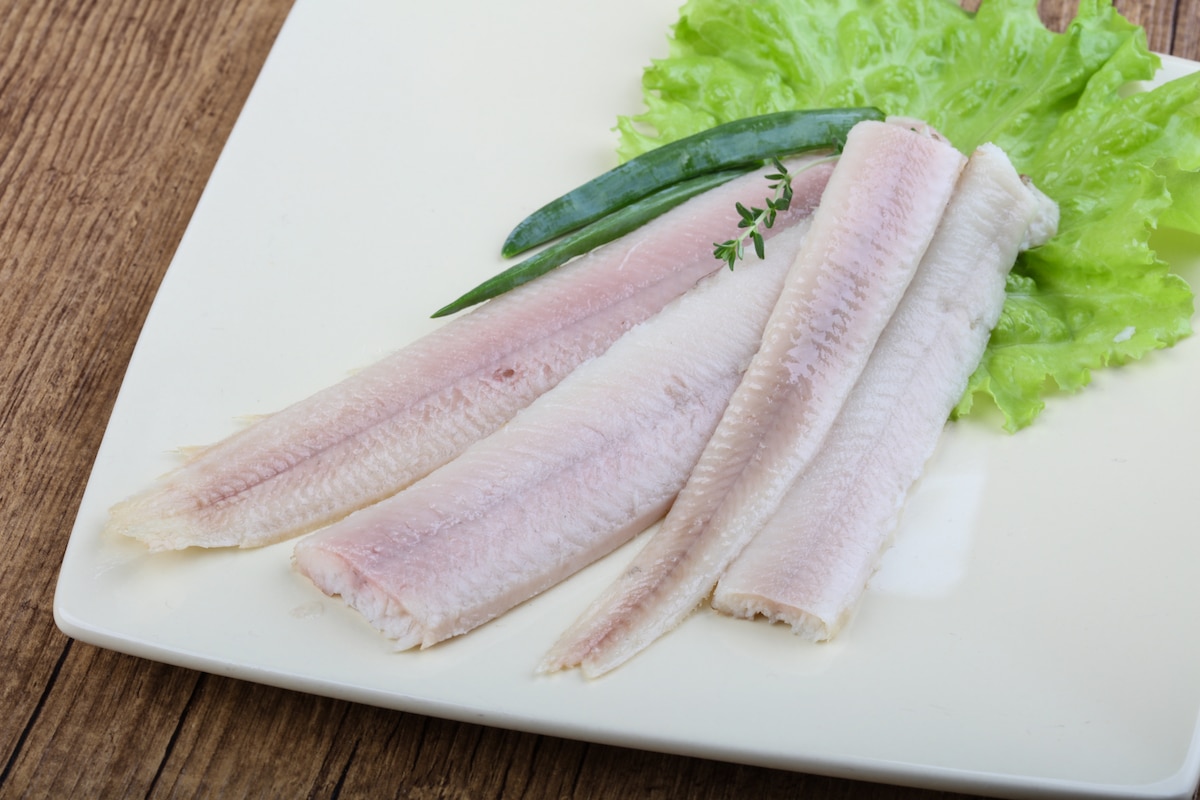 Smoked eel filets on a white plate with lettuce