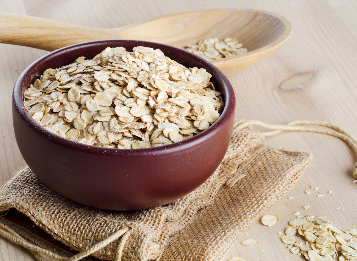 Rolled oats in a red bowl on a wooden background.