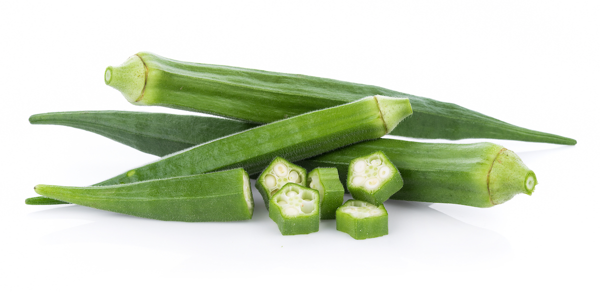 Three whole fresh okra pods plus one sliced into cross-sections on a white background