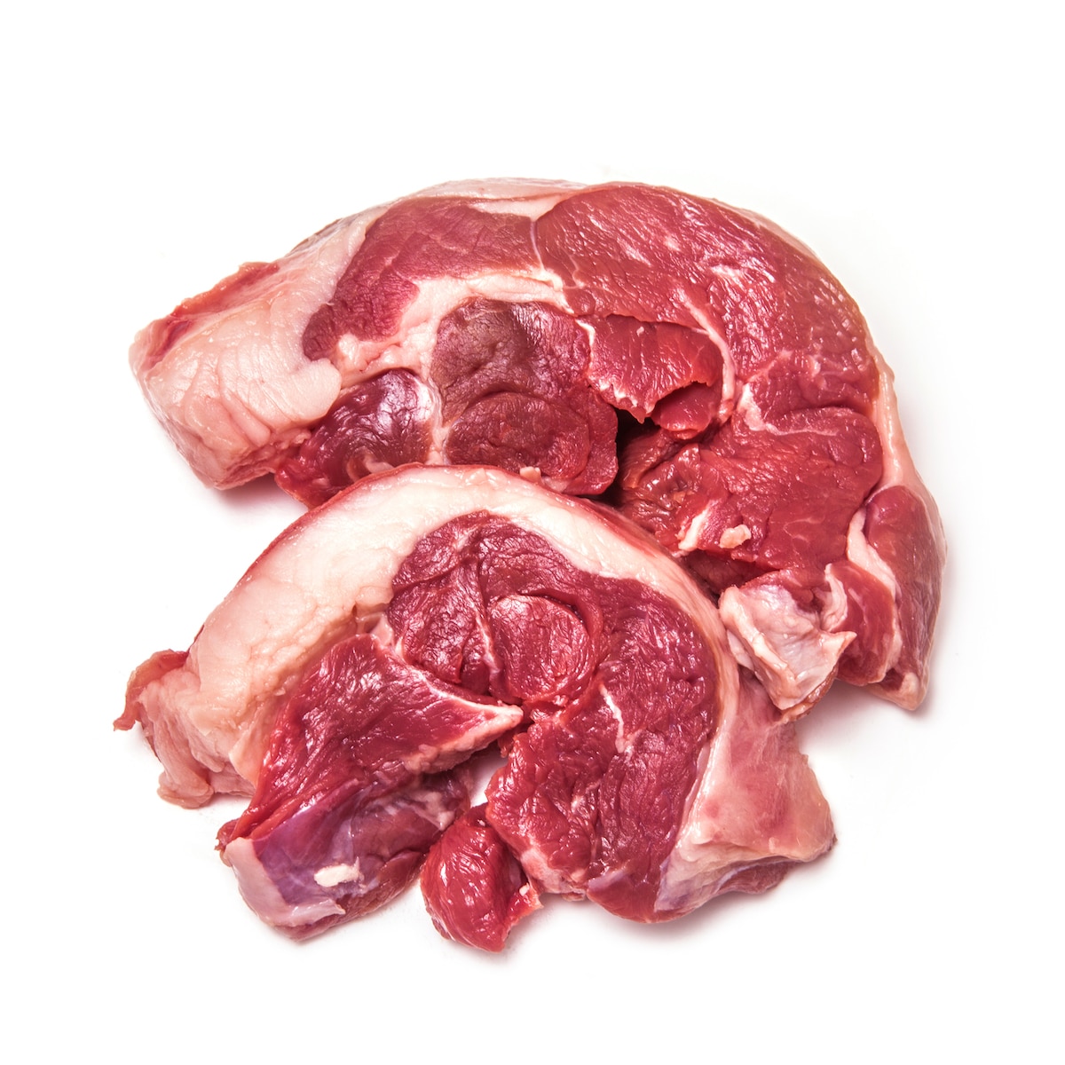 Raw goat leg steaks on a plain white background