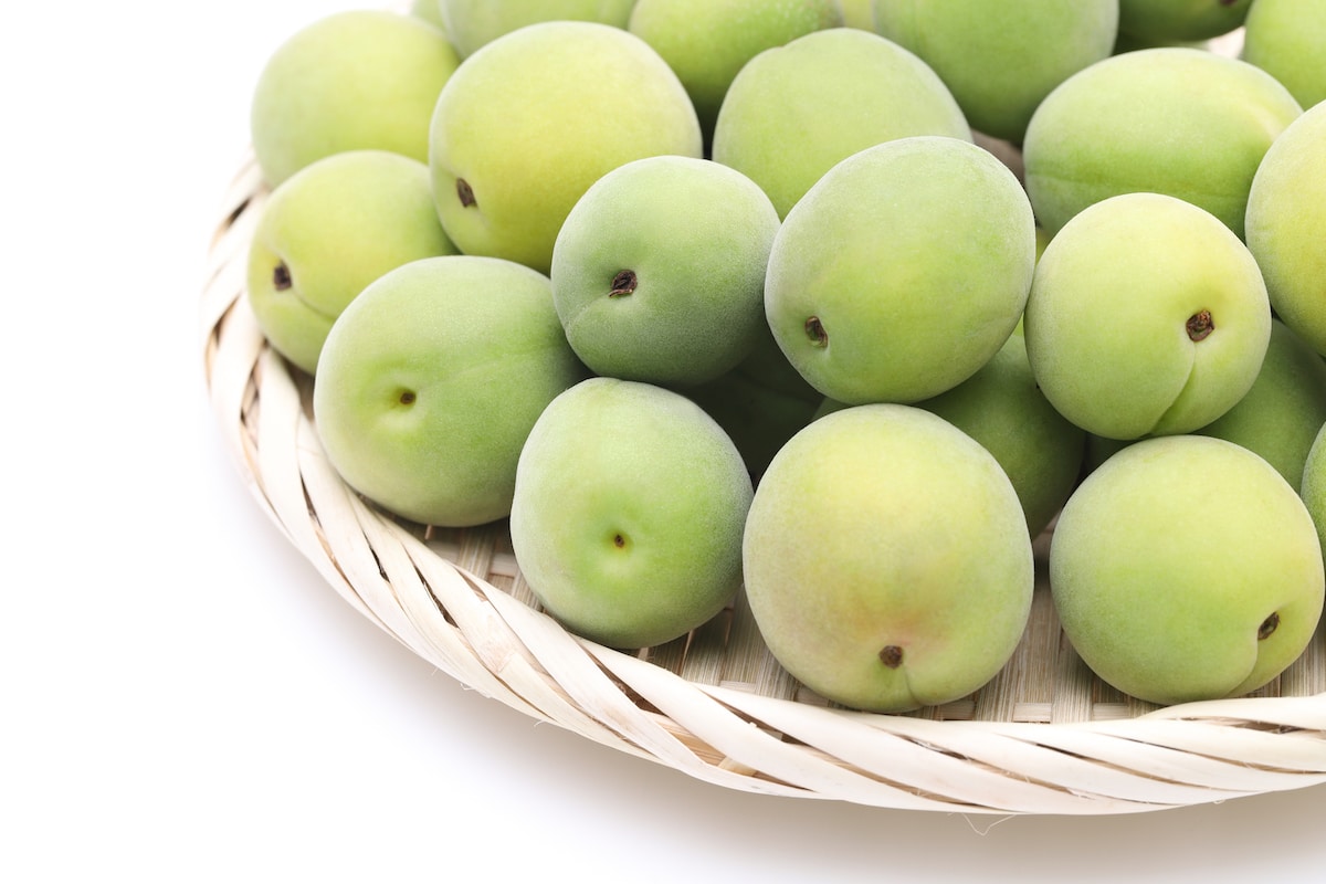 Pile of green fresh ume plums in a wicker basket