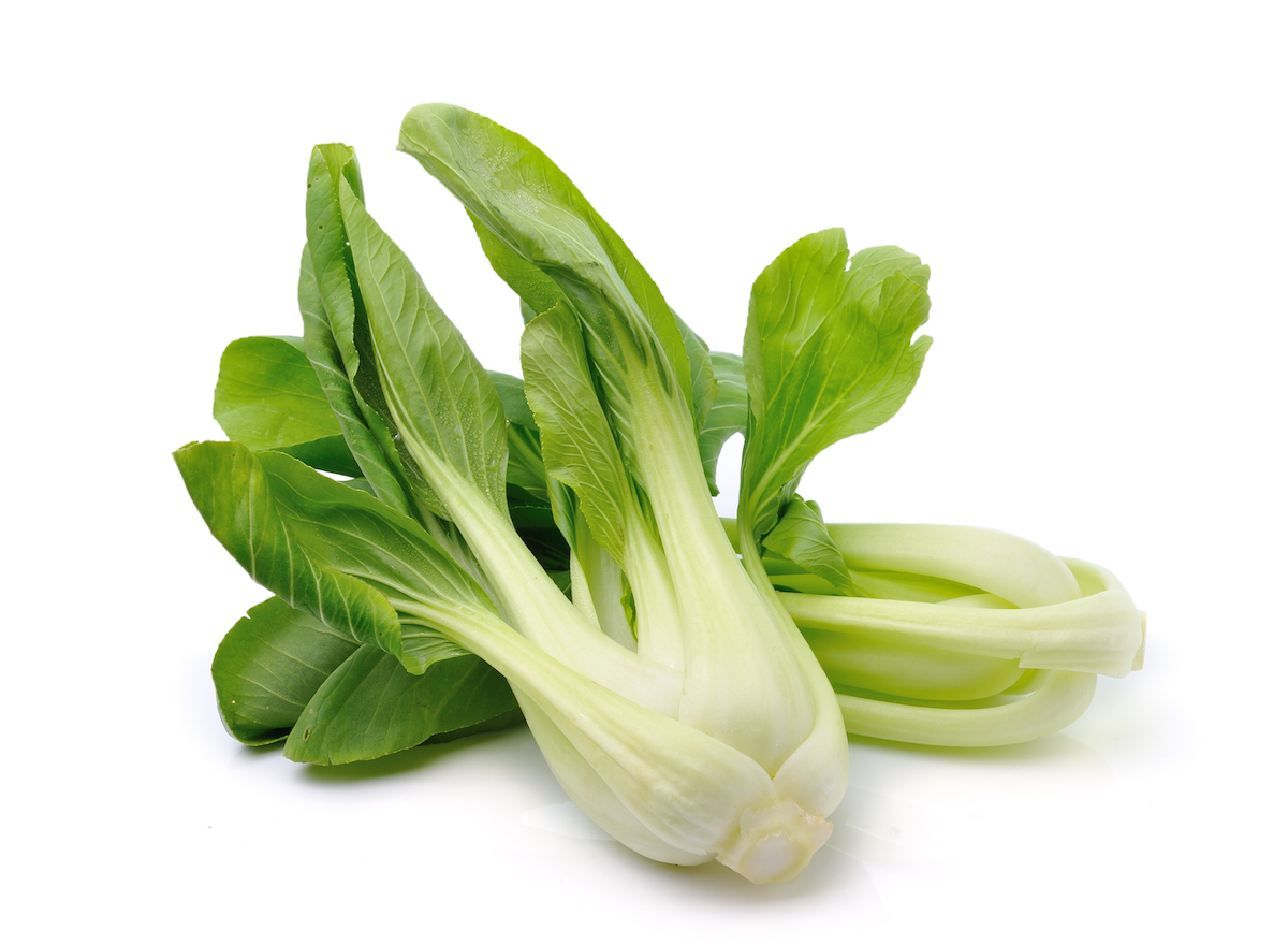 Two heads of fresh raw bok choy on a white background