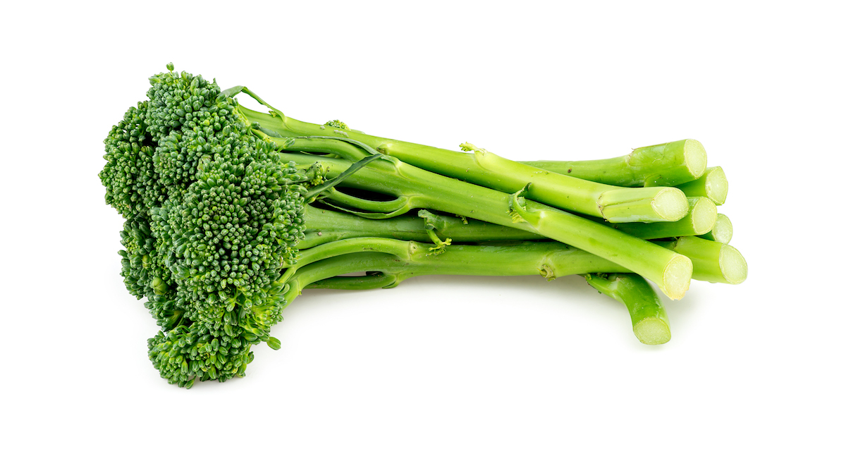 One bunch of raw broccolini on a white background.