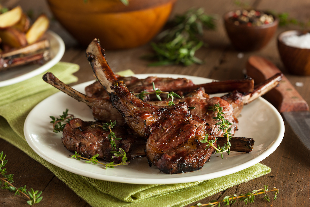Stack of grilled lamb chops on a large white plate.