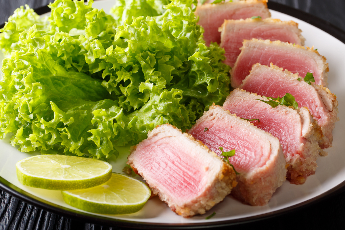 Seared ahi tuna on a white plate with salad on the side