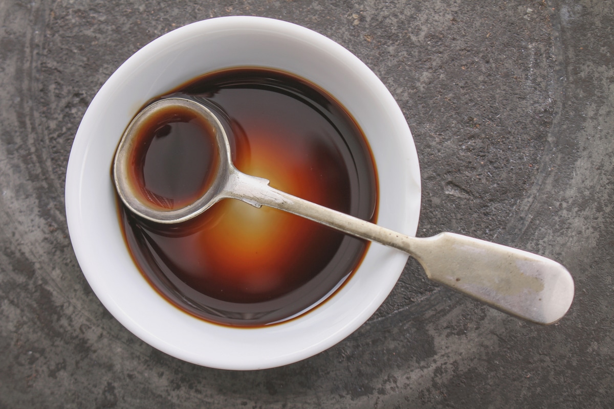 Worcestershire sauce in a small white bowl with metal spoon